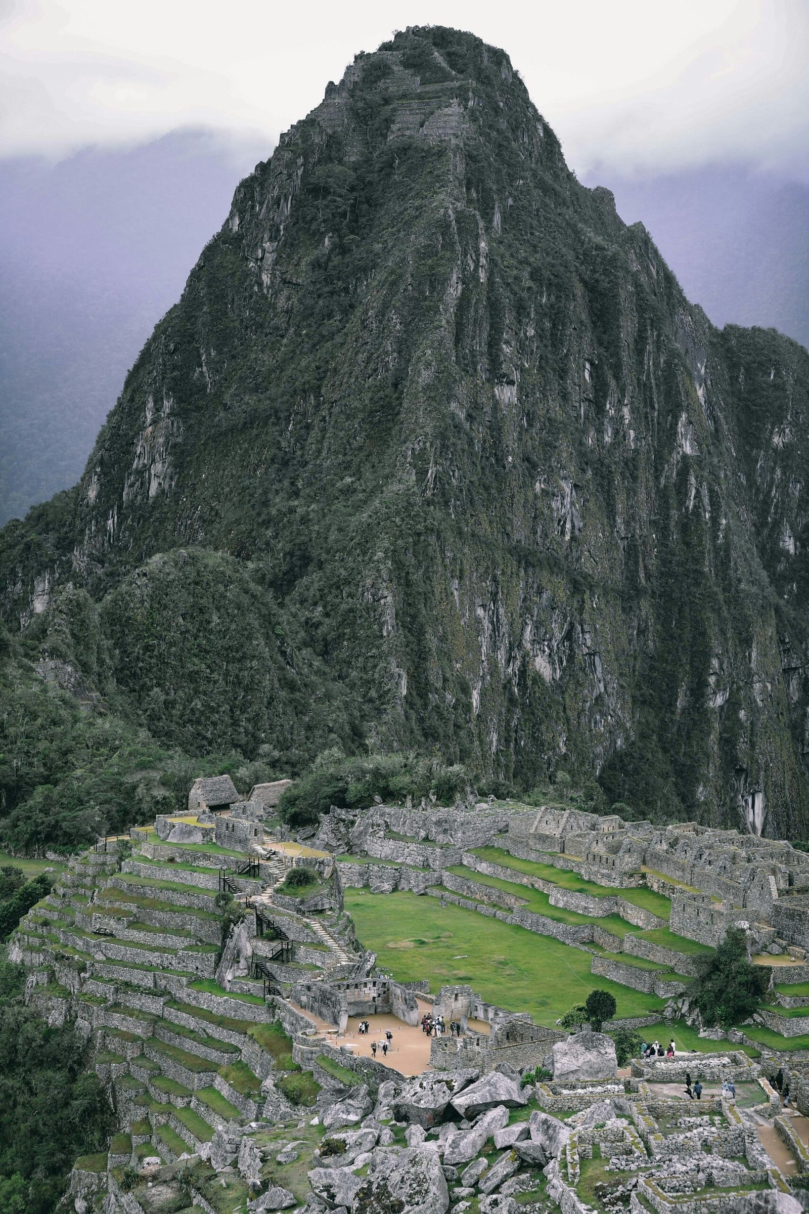 Vista panorámica de la ciudadela de Machu Picchu con sus terrazas agrícolas, zona urbana y la icónica montaña Huayna Picchu elevándose majestuosamente entre bruma andina